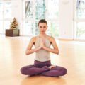 A woman in the lotus position (Padmasana) meditating with her hands in prayer position (Anjali Mudra)