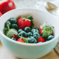 A porcelain bowl with strawberries and blueberries